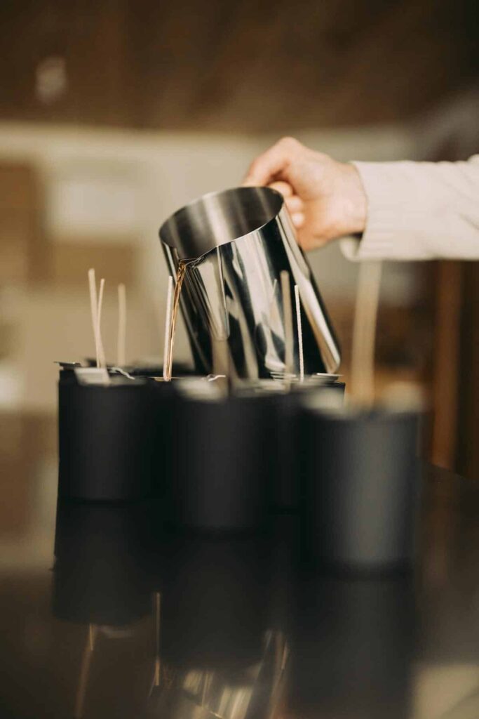Coulée artisanale de la cire de tournesol dans les pots noirs à l'atelier